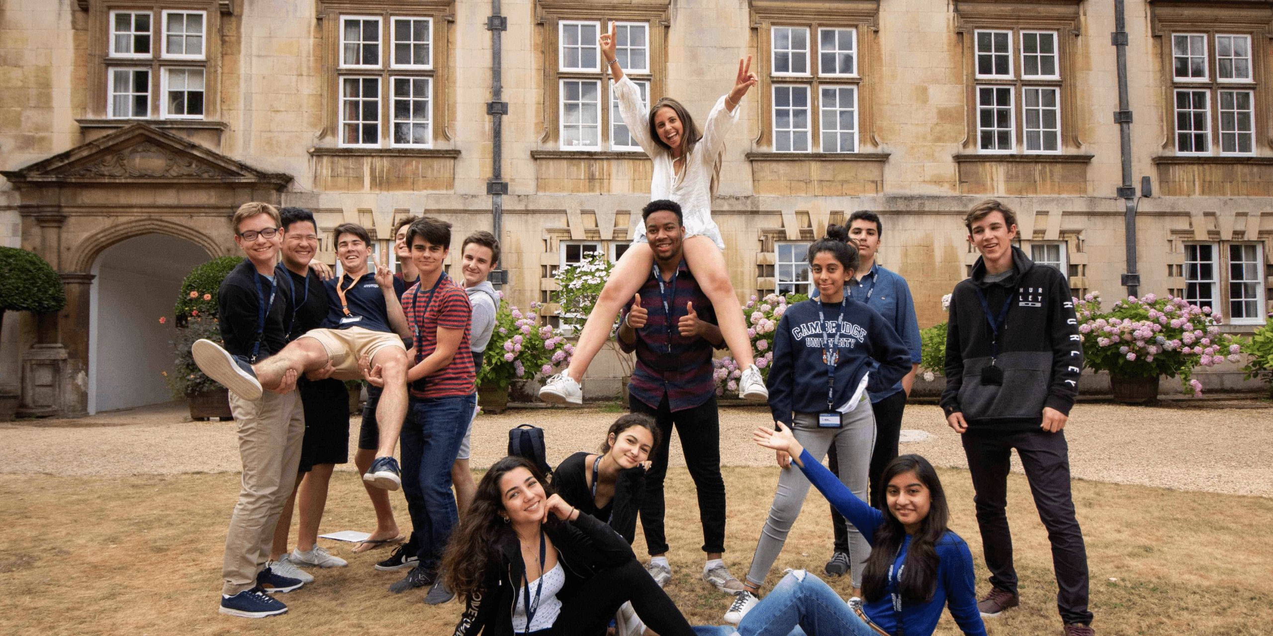 Group photo of students standing in front of a Cambridge University building.