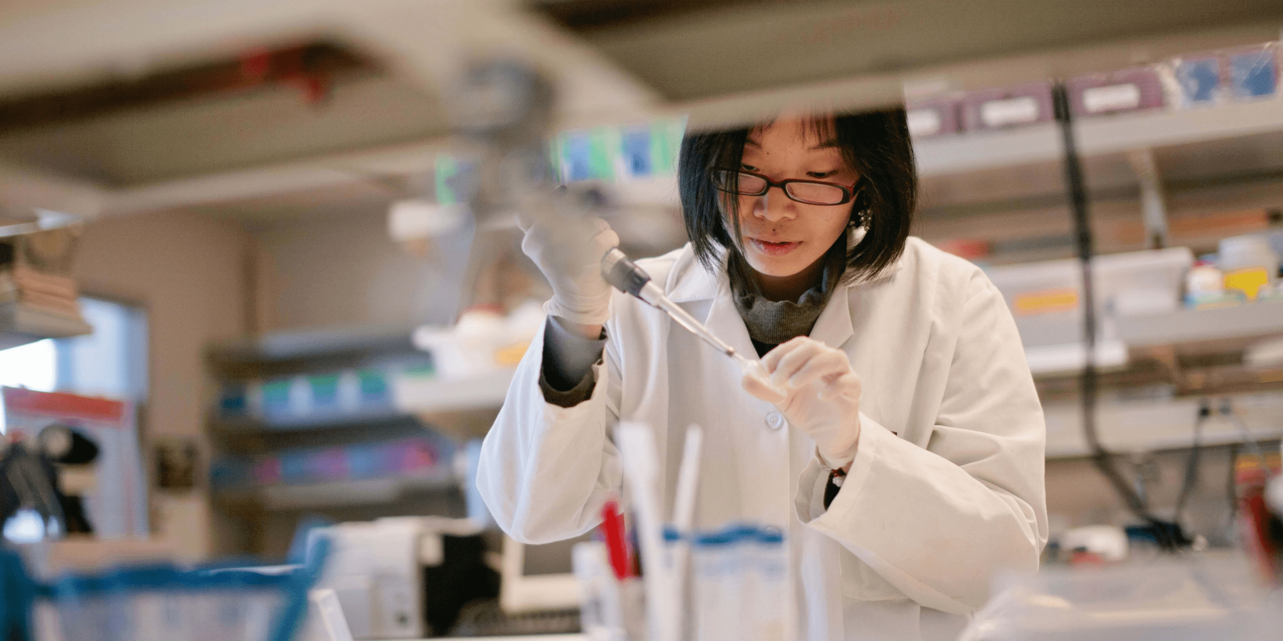 A woman wearing a lab coat, experimenting.