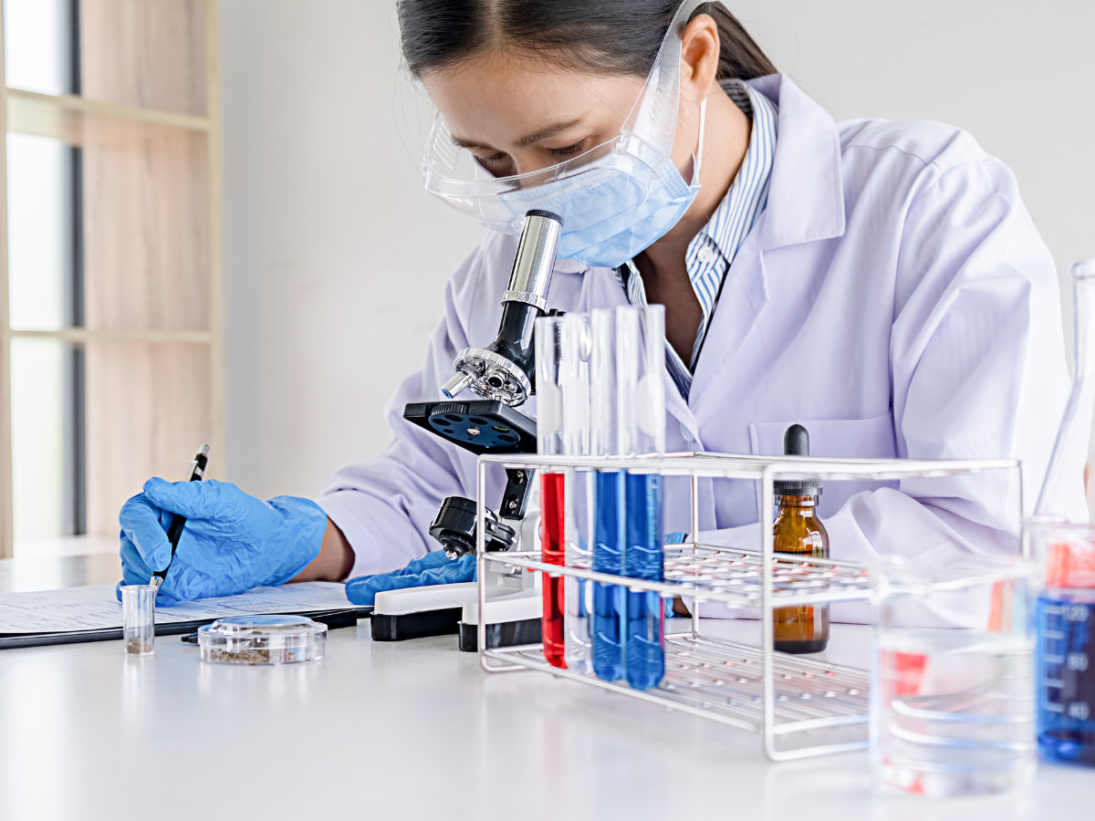 A woman wearing a labcoat experimenting