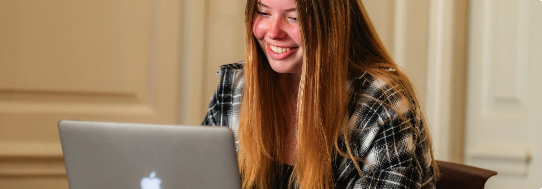 A woman smiling at her laptop