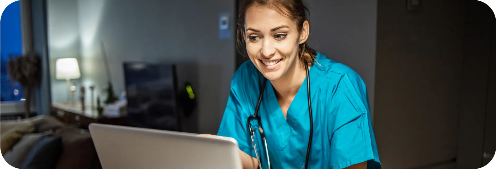 a nurse smiling while looking at a laptop