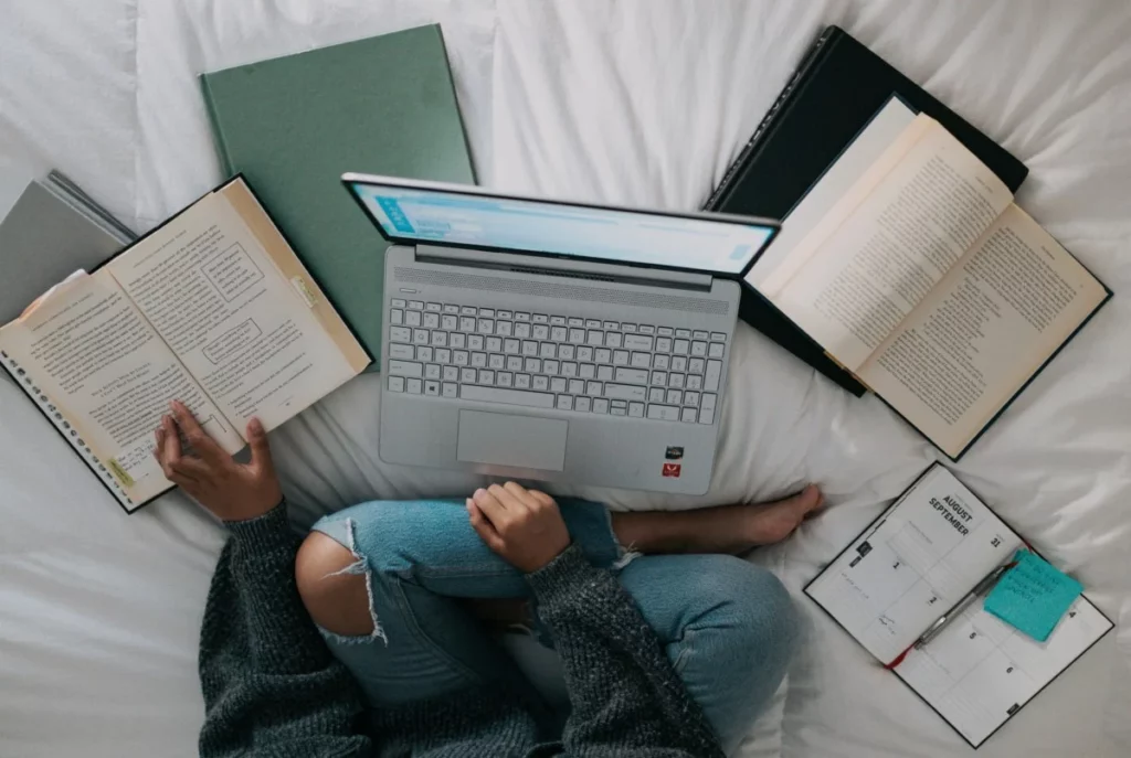 Creative writing student surrounded by notepads using laptop to respond to a prompt