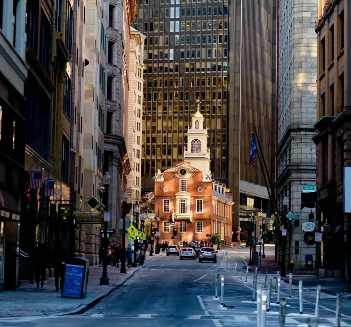 A stately historic building in Boston with a large clock tower and architectural details in red brick and white stone.
