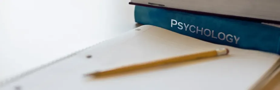 A set of psychology study tips displayed on a laptop screen, surrounded by study materials such as books and notes.
