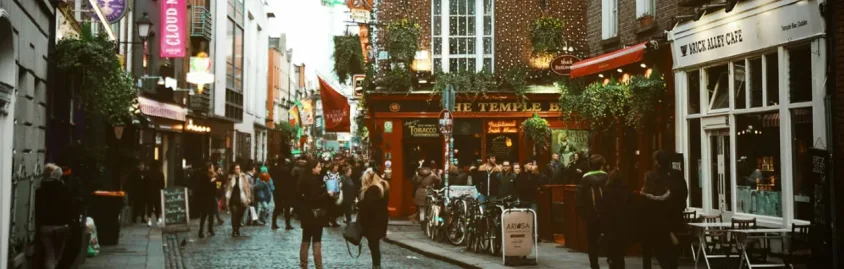 A scenic view of Dublin, Ireland, with a river and a mix of historic and modern buildings under a cloudy sky.