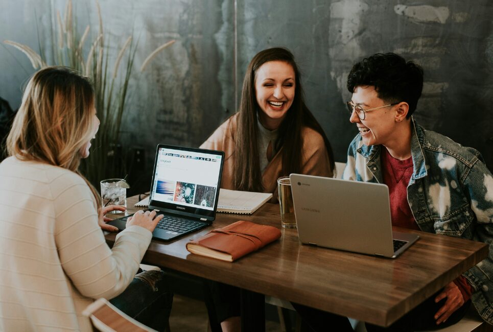 Three women with laptops laughing 