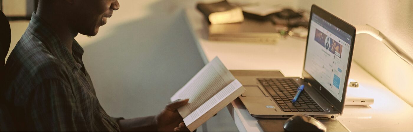 Student sitting at desk with study book and laptop