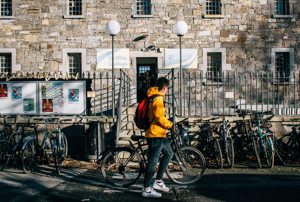 Student with yellow jacking parking bike outside Dublin college