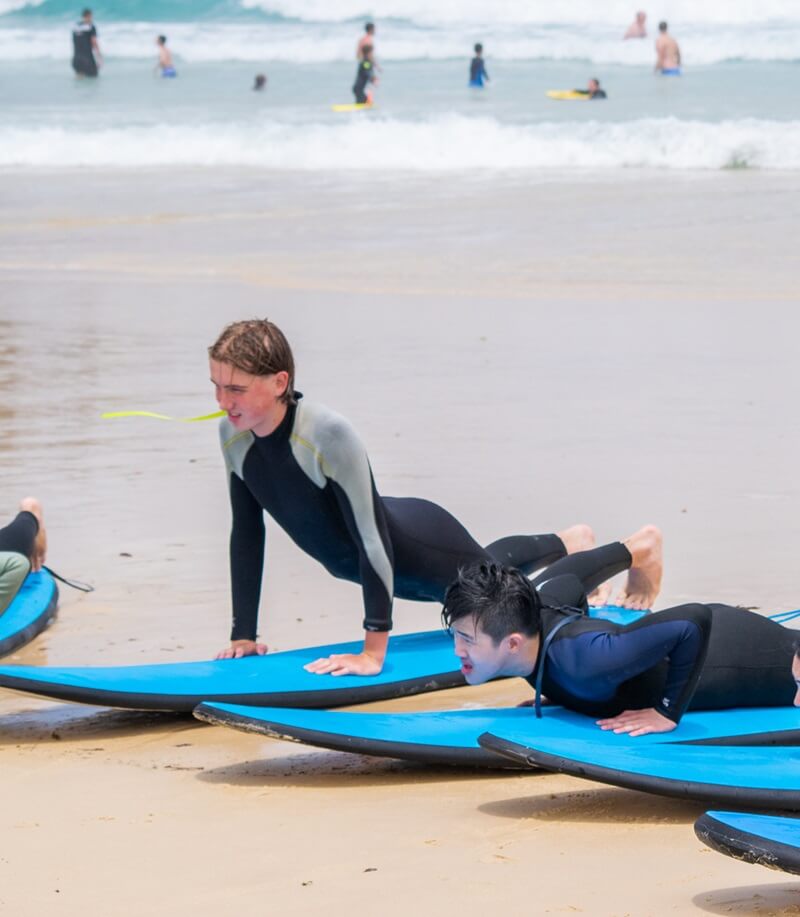 Students practising on Bondi beach during a surfing class during a Sydney summer school excursion